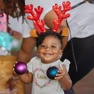 girl wearing reindeer antlers and holding ornaments at a toy drive in Denver, Colorado